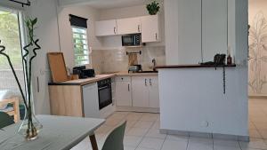 a kitchen with white cabinets and a table and a table and a table at Coeur de Rhoda in Saint-François