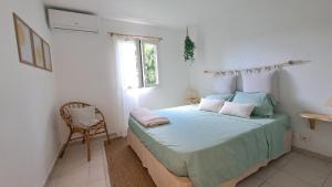 a bedroom with a bed with a chair and a window at Coeur de Rhoda in Saint-François