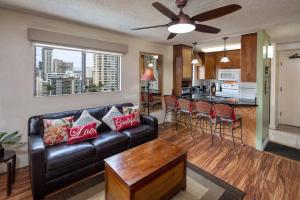 a living room with a black leather couch and a kitchen at HEART of WAIKIKI,1BDRM,FREE PARKING, WIFI,NO RESORT FEES,YOUTUBE,NETFLIX ! in Honolulu