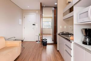 a living room with a couch and a kitchen at Flats Osasco Trade Center in Osasco