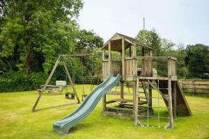 a playground with a slide and a play structure at Birch Cottage - Tranquil Country Cottage with Indoor Swimming Pool in Haverfordwest