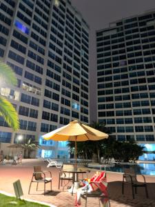 a table and chairs with an umbrella in front of buildings at Departamento Punta Centinela frente al mar in Santa Elena