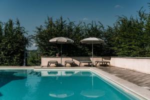 a swimming pool with two chairs and two umbrellas at Le Suite di Borgo Casa Scaparone in Biglini