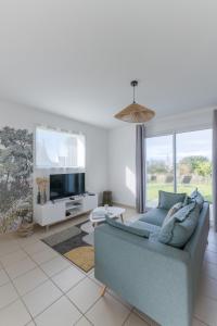a living room with a blue couch and a tv at AN 19 - Charmante maison a 300m de la mer in Porspoder