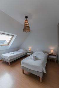 two beds in a white room with a window at AN 19 - Charmante maison a 300m de la mer in Porspoder