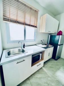 eine kleine Küche mit Spüle und Kühlschrank in der Unterkunft PJ Hostel & Bar in Pattaya