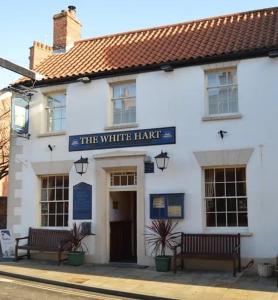 a white building with two benches in front of it at The White Hart in Caistor