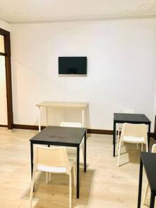 two black tables and white chairs in a room at Private Room 103 in Guest House da Fonte in Figueira da Foz