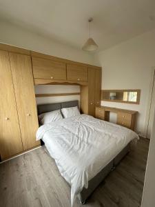1 dormitorio con 1 cama blanca grande y armarios de madera en Abigail house, en Westhoughton 17 fotos más