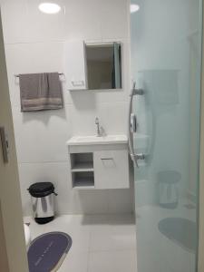 Un baño blanco con lavabo y espejo. en Suítes Mirantes Das Baleias, en Arraial do Cabo