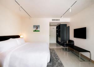ein Schlafzimmer mit einem Bett und einem Flachbildfernseher in der Unterkunft The StandardX, Bangkok Phra Arthit in Bangkok