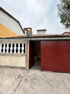 a garage with a red door and a building at Casa Temporada S P Aldeia sem TV in São Pedro da Aldeia