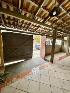 an empty garage with a wooden door and a car parked at Casa Temporada S P Aldeia sem TV in São Pedro da Aldeia