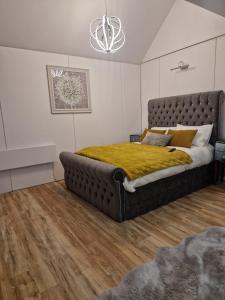 a bedroom with a large bed with a yellow blanket at Ty Branwen in Cowbridge