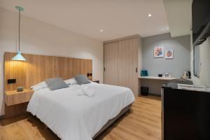 a bedroom with a large white bed and a kitchen at Casa Origo Hospedaje in Medellín