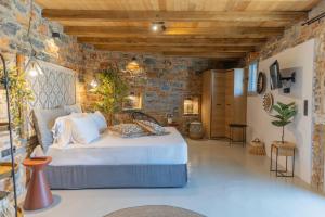 a bedroom with a bed and a stone wall at Harmony Luxury Villas Naxos in Kastraki Naxou