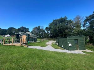 a couple of green buildings in a grass field at Yurt in Hayle