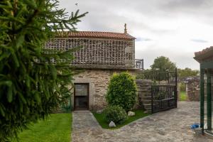 a stone house with a gate and a yard at Casa Horreo lar san Adrián in A Coruña +14 photos
