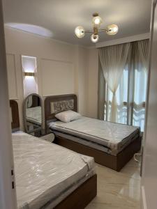 une chambre avec deux lits et une fenêtre dans l'établissement القاهرة الجديدة مدينتي, à Madinaty