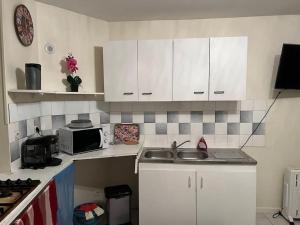 a kitchen with white cabinets and a sink and a microwave at Appartement en centre-ville in Roissy-en-France