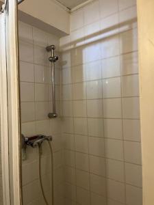 a white tiled shower with a hose in a bathroom at Appartement en centre-ville in Roissy-en-France