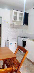 a kitchen with a table and a stove and refrigerator at Three A Diárias in Mata de Sao Joao