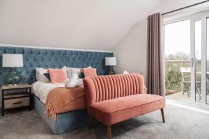 a bedroom with a bed and a chair and a window at Waveside-Waterside with hot tubResort PoolGym in Padstow