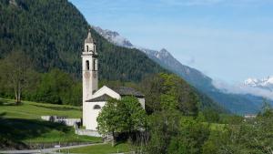 a small white church in a field with a mountain at Haus in den Bergen in Borgonovo