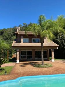 een huis met een palmboom voor een zwembad bij Sitio Entre Rios in Guaporé