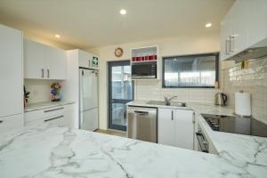 a white kitchen with a marble counter top at Handy Location, Ocean & Mountain Views, Spacious Yard - KK46451 in Kaikoura