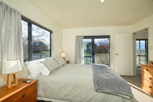 a bedroom with a large bed and large windows at Handy Location, Ocean & Mountain Views, Spacious Yard - KK46451 in Kaikoura