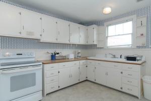 a white kitchen with white cabinets and a sink at Craft Upper Unit by Bryant Real Estate in Wrightsville Beach