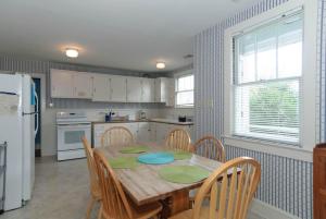 a kitchen with a wooden table with chairs and a refrigerator at Craft Upper Unit by Bryant Real Estate in Wrightsville Beach