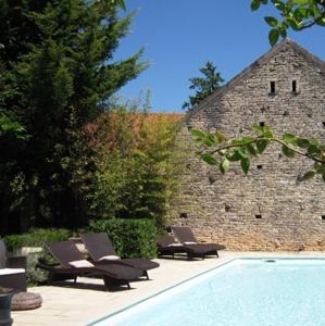 two lounge chairs and a swimming pool next to a stone building at Les Demoiselles de Ladoix in Ladoix Serrigny