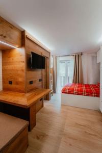 une chambre avec deux lits et un bureau avec une télévision dans l'établissement Monolocale La casa delle fate, à Madonna di Campiglio