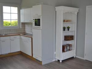 Una cocina blanca con gabinetes blancos y una ventana. en Bungalow in Zeeland near the Beach, en Breskens