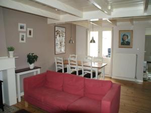 a living room with a red couch and a table at Historic Cottage w Garden in Breskens