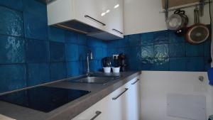 a kitchen with a sink and a blue tiled wall at Le casette in Monopoli