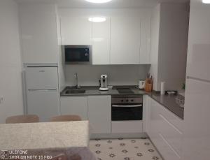 a white kitchen with a sink and a stove at La Casita de Usaya in Ezcaray