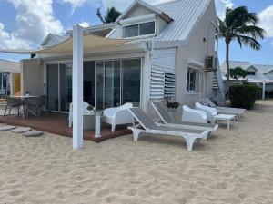 a house on the beach with chairs and a table at Sweet Home SXM Baie Nettlé Pieds dans l'eau in Baie Nettle
