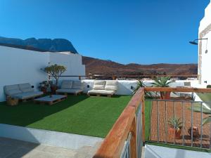 a patio with couches and chairs on a balcony at Casa Bailarina, romantický kamenný dům s úžasným výhledem na oceán in Agaete