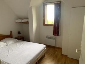 a bedroom with a white bed and a window at Appartement dans Résidence Bois de la Reine, Besse et Saint Anastaise in Besse-et-Saint-Anastaise