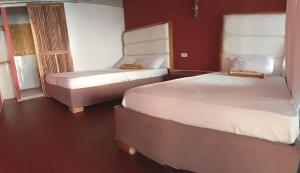 two beds in a room with red walls at Cabañas Palos Locos in Barú +50 photos