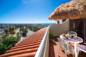 a balcony with a table and a straw umbrella at Sol Brilhante in Albufeira