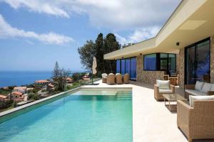 a villa with a swimming pool and a house at Villa Ohana in Estreito da Calheta