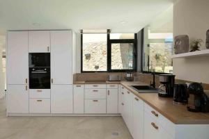 a kitchen with white cabinets and a large window at Villa Ohana in Estreito da Calheta