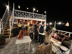 a group of people standing on a deck at night at West coast surf house in Imsouane