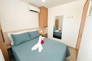 a bedroom with a blue bed with a white ribbon on it at Aconchego, varandinha e vista mar em Maracaípe in Porto De Galinhas