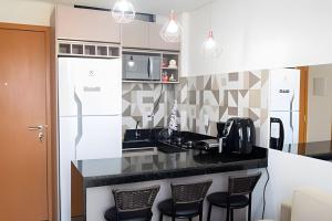 a kitchen with a black counter and stools at Aconchego, varandinha e vista mar em Maracaípe in Porto De Galinhas +38 photos