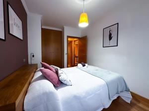 a bedroom with a large white bed with pink pillows at Apartamento con garaje, céntrico y luminoso in Pontevedra